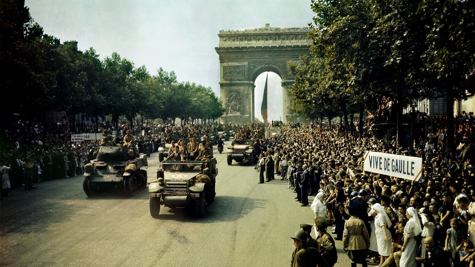 Crowds line the Champs-Elysees toward the Arc de Triomphe as Free French armour passes after the liberation of Paris, August 1944.