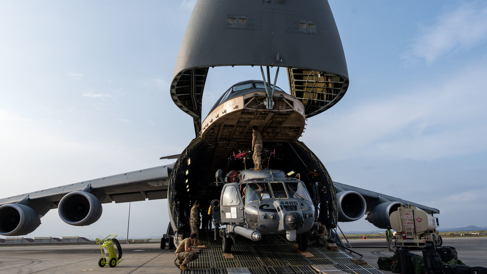 U.S. Airmen with the 303rd Expeditionary Rescue Squadron load an HH-60W Jolly Green II into a C-5M Super Galaxy at Camp Lemonnier, Djibouti, October 2023